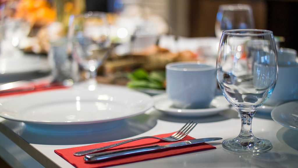 Wine glasses, cutlery and some food displayed inside a restaurant in a closeup photo.